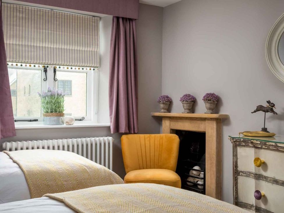 A bedroom with twin beds and a yellow chair at Lavender Cottage (Stow-on-the-Wold) Cheltenham
