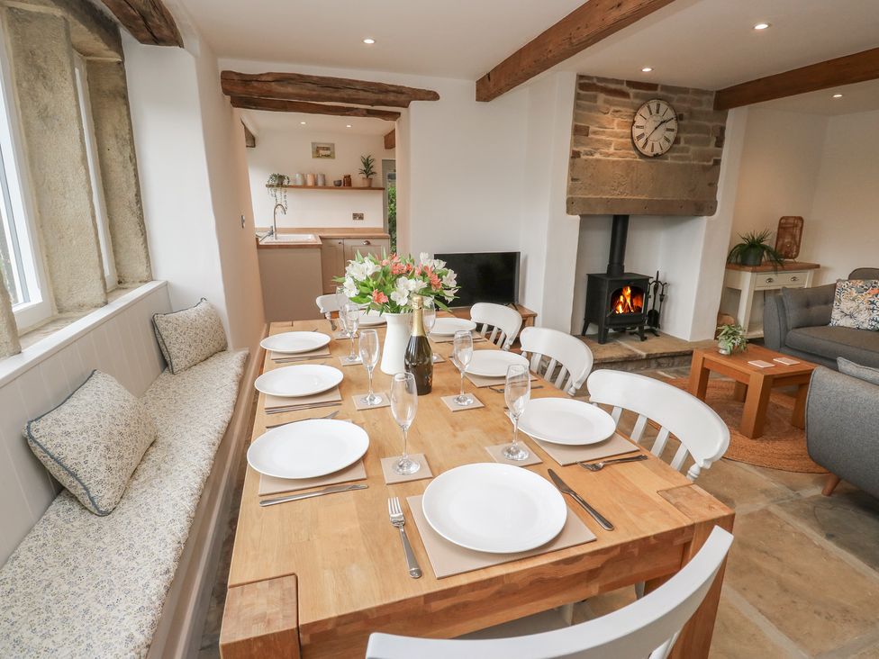 A dining room with a table, chairs and a fireplace at 6 Well Hill in Holmfirth