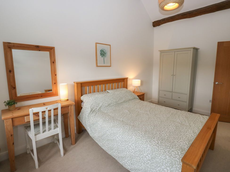 A bedroom with a bed, desk, mirror and wardrobe at 6 Well Hill Holmfirth
