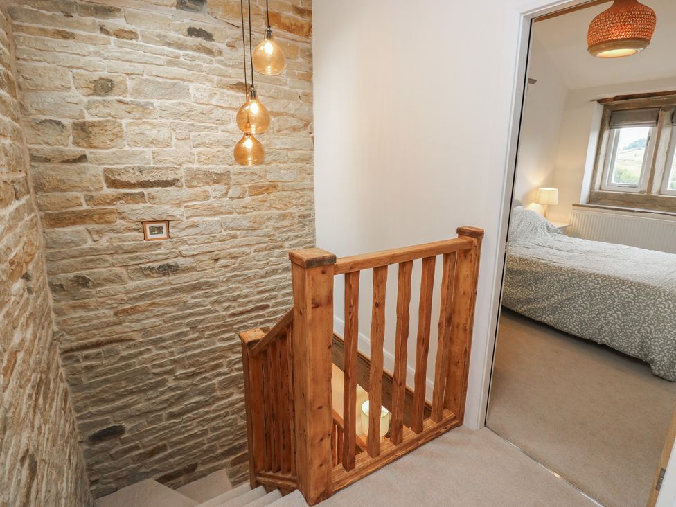 A staircase with a wooden railing and light fixtures at 6 Well Hill Holmfirth