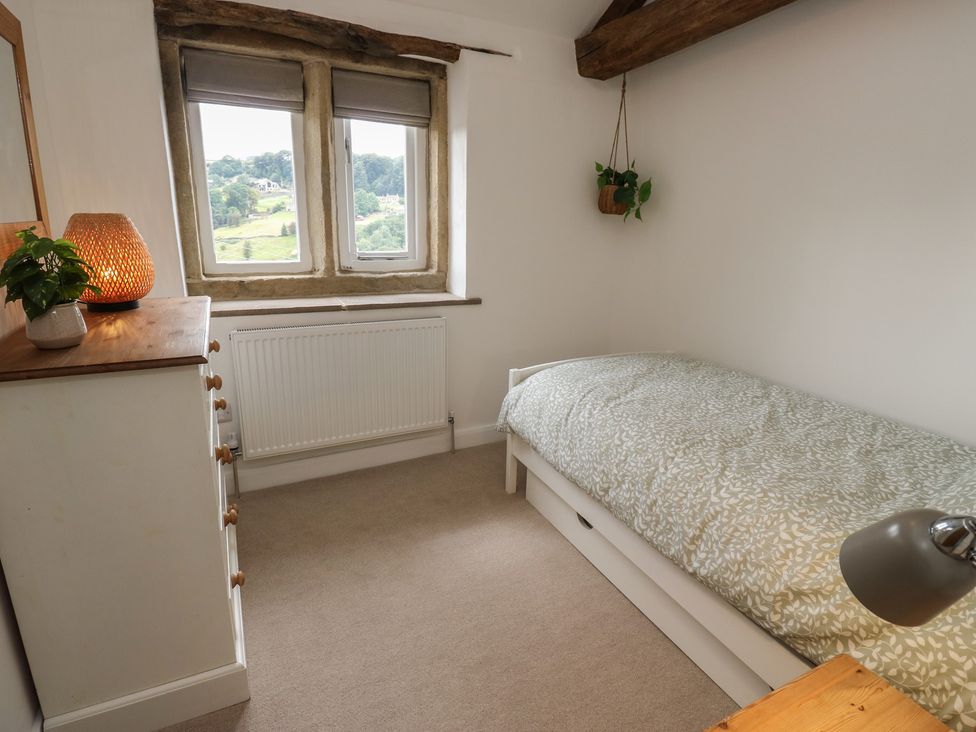 A bedroom with a bed, table, and window at 6 Well Hill in Holmfirth