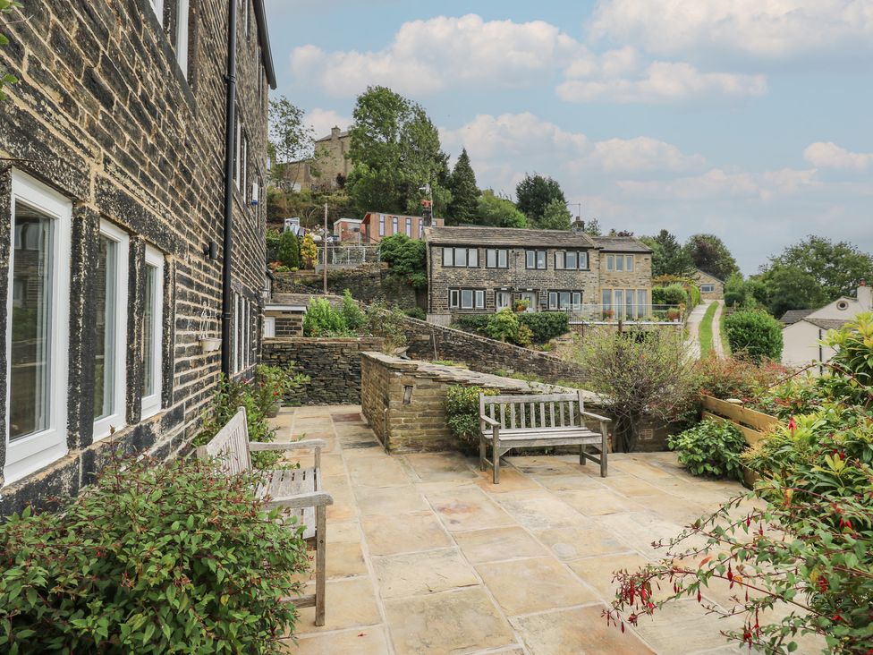 An outdoor area with a stone wall and benches at 6 Well Hill Holmfirth