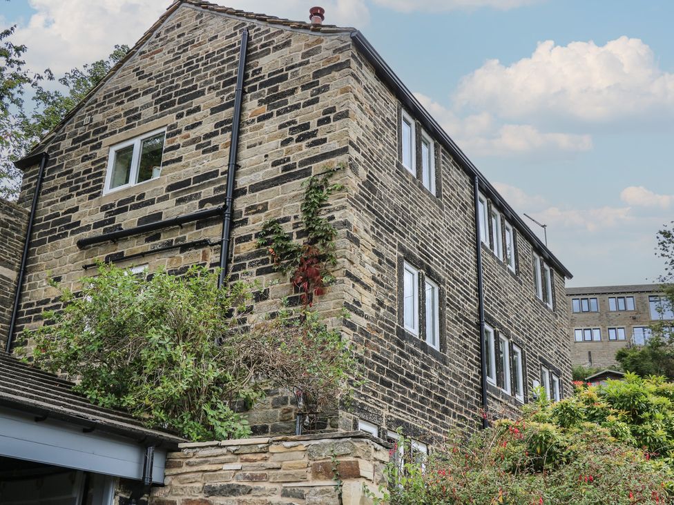 A brick house with windows and plants at 6 Well Hill in Holmfirth