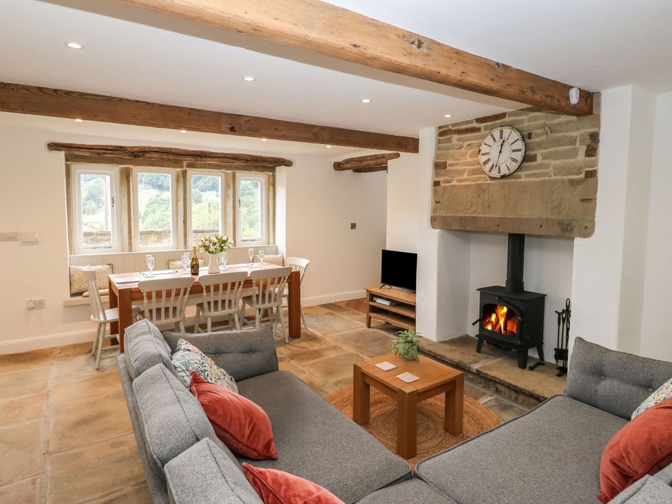 A living room with a sofa and dining area at 6 Well Hill in Holmfirth
