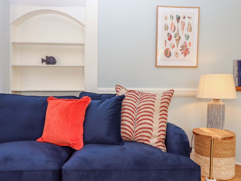 A living room with a navy sofa and decorative items at The Porthole in Newton Ferrers