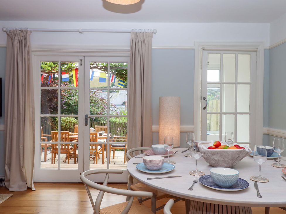 A dining room with a table set for meals at The Porthole in Newton Ferrers