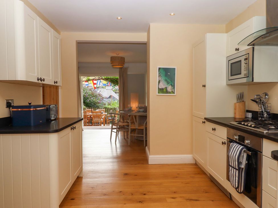 A kitchen with appliances and a view into a dining area at The Porthole in Newton Ferrers