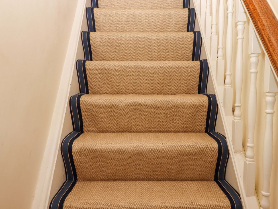 A staircase with carpet and handrail at The Porthole in Newton Ferrers
