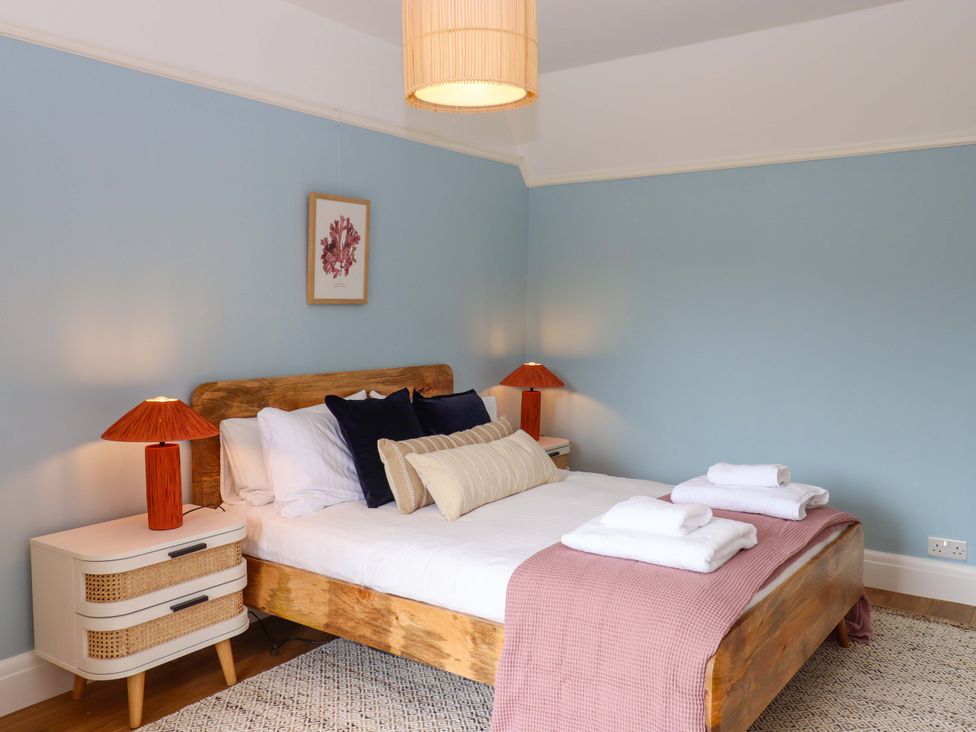A bedroom with a bed and nightstands at The Porthole in Newton Ferrers
