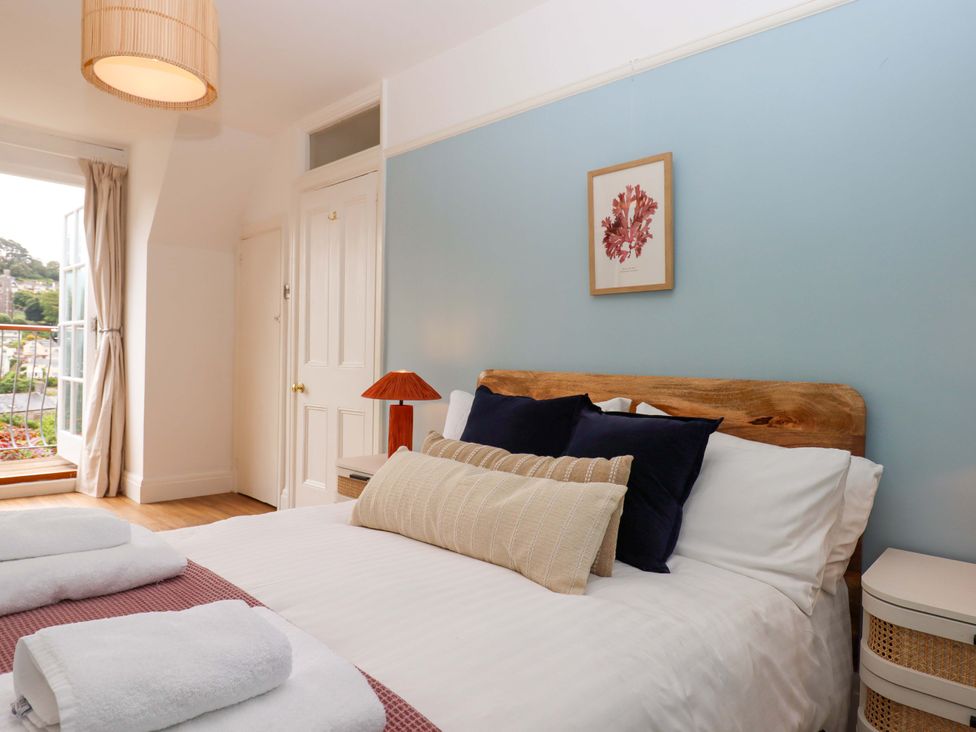 A bedroom with a bed and a lamp at The Porthole in Newton Ferrers