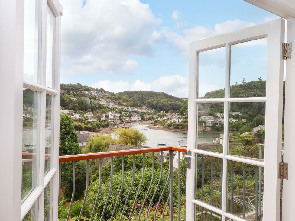A balcony overlooking a river and houses at The Porthole in Newton Ferrers