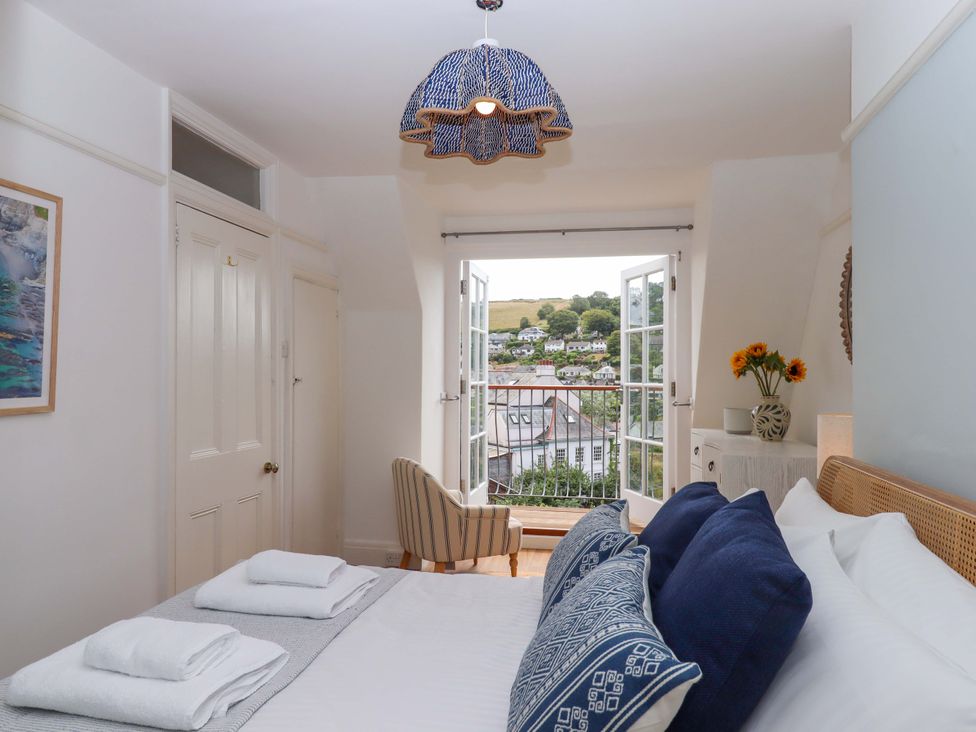 A bedroom with a bed, chair, and flowers at The Porthole in Newton Ferrers