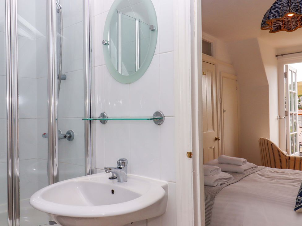 A bathroom with a shower and washbasin at The Porthole in Newton Ferrers
