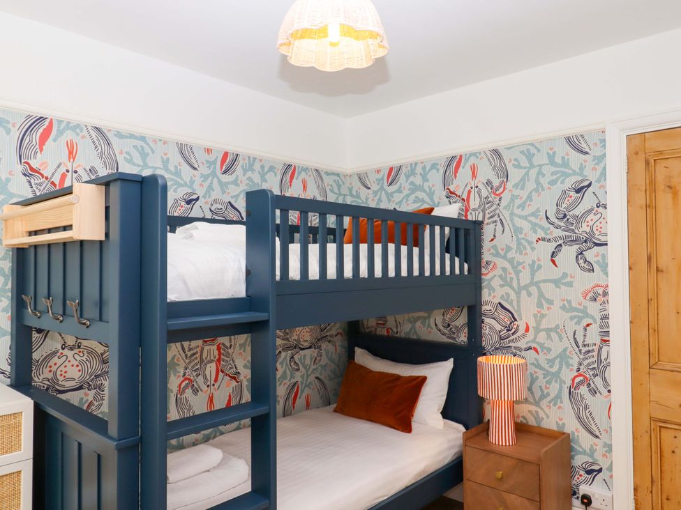 A bedroom with a bunk bed and nightstand at The Porthole in Newton Ferrers