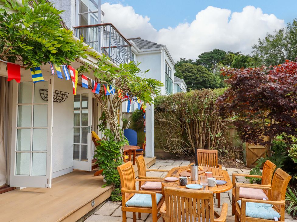 A garden with a table and chairs and flag decorations at The Porthole in Newton Ferrers