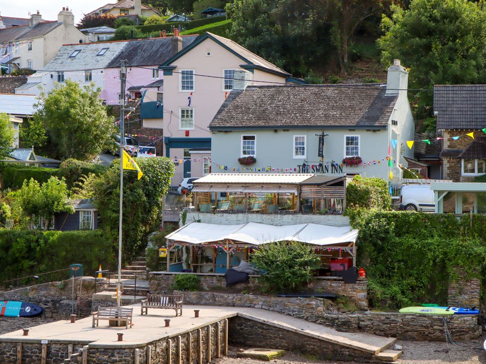 An outdoor view of a restaurant building with a patio and decorations at The Porthole in Newton Ferrers