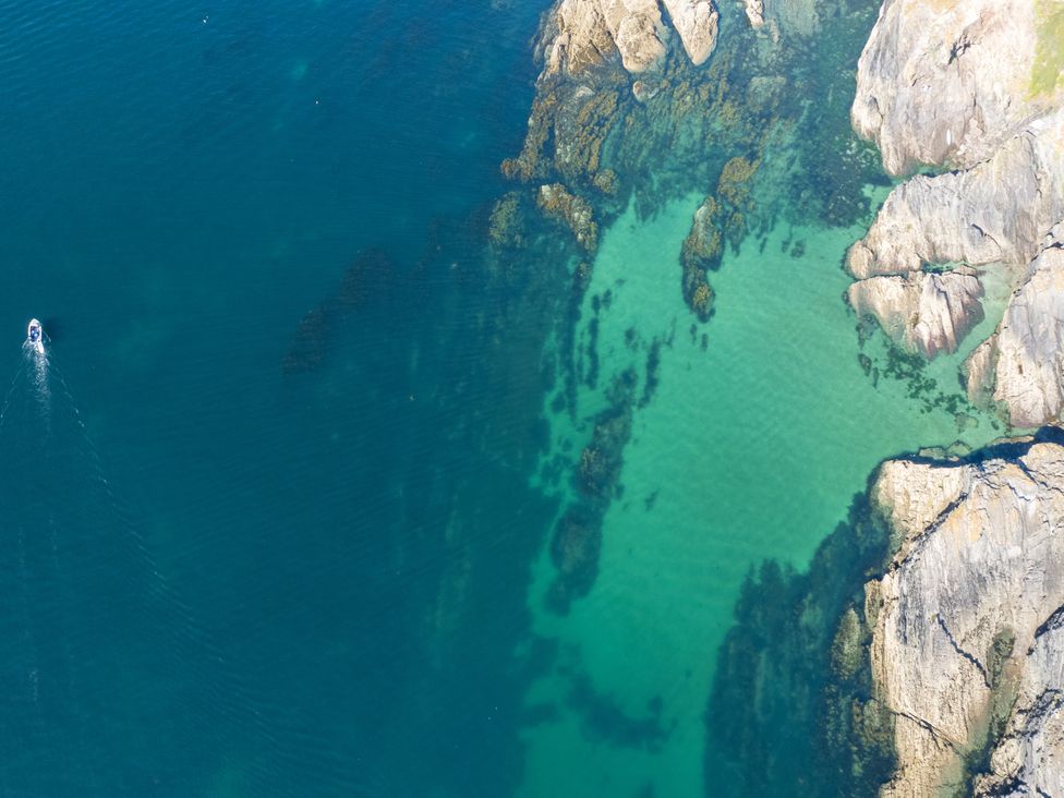 An aerial view of a boat on water near rocks at The Porthole in Newton Ferrers