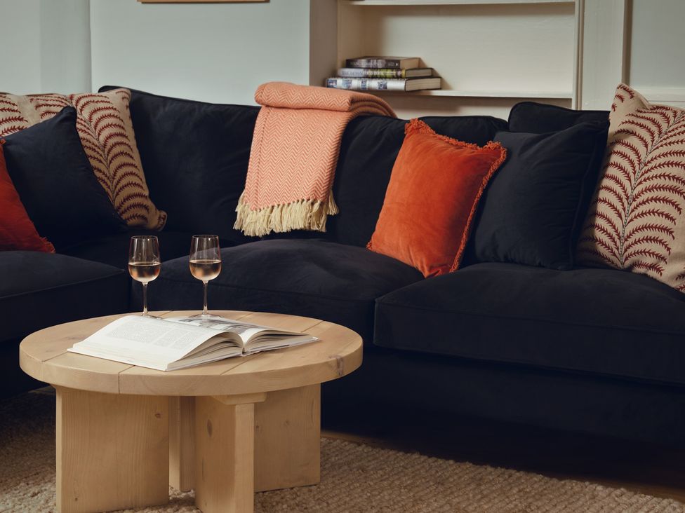A living room with a black sofa and a coffee table at The Porthole in Newton Ferrers