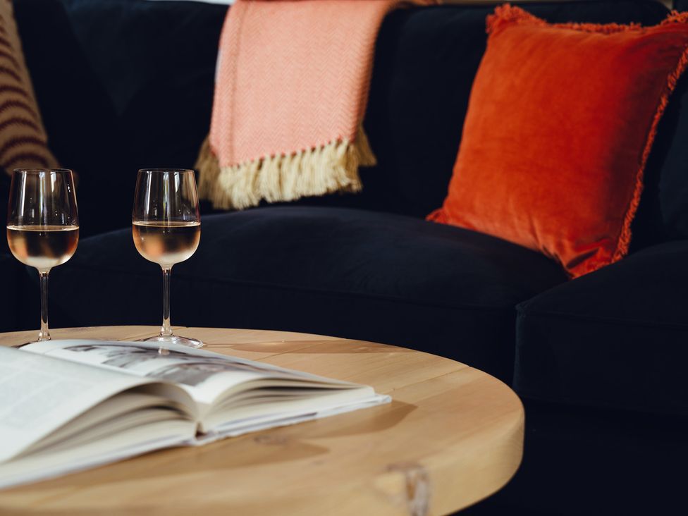 A living room with wine glasses and a book at The Porthole in Newton Ferrers