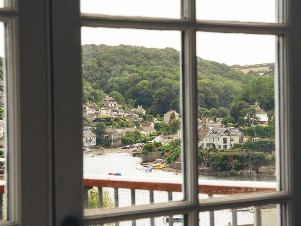 A view of houses and a river through a window at The Porthole in Newton Ferrers
