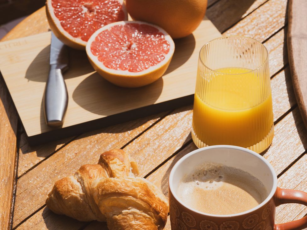 A breakfast setting with grapefruit, croissant and drinks at The Porthole in Newton Ferrers