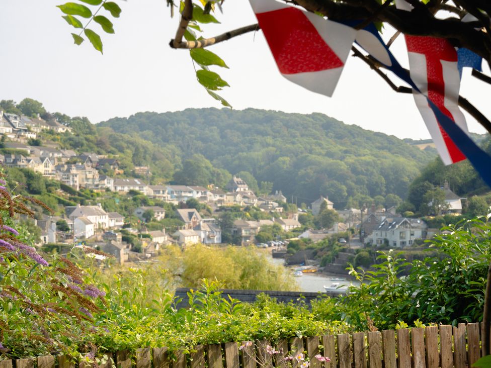 A view of houses and hills with flags in a garden at The Porthole in Newton Ferrers