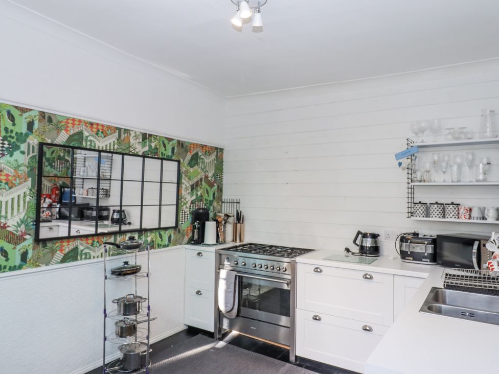 A kitchen with a stove, sink, and mirrored wall at 26 Above Town in Dartmouth