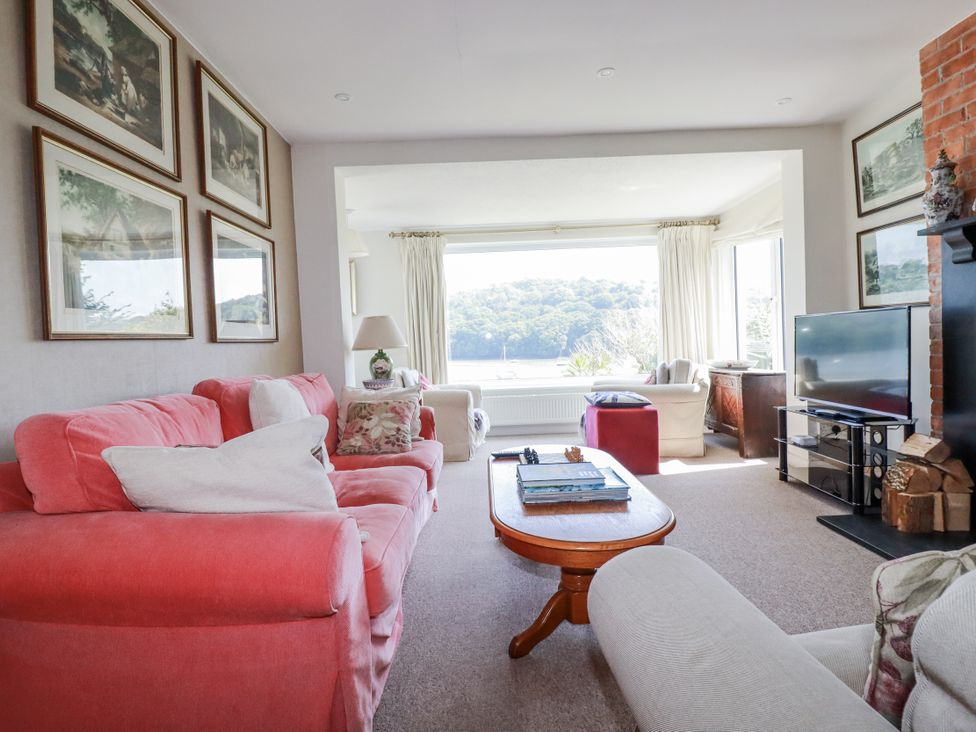 A living room with a sofa, coffee table, and television at Kiln Cottage in Golant near Tywardreath