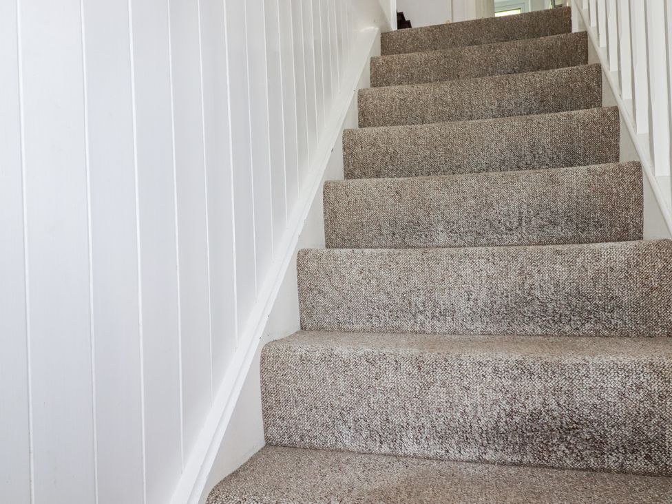 A staircase with carpet and white walls at Kiln Cottage Golant near Tywardreath