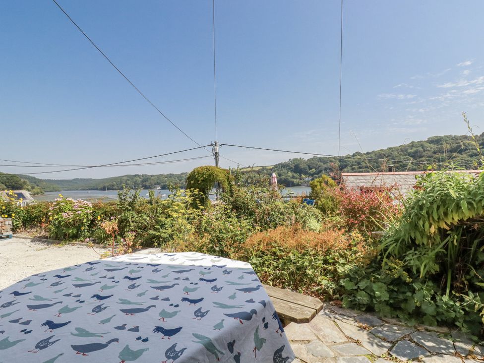 An outdoor area with a table and flowers near a river at Kiln Cottage Golant near Tywardreath
