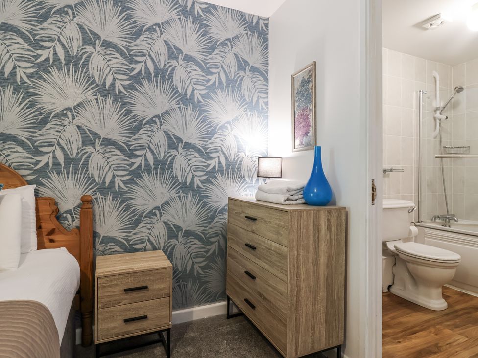 A bedroom with a dresser and a bathroom visible at Valley Lodge 20, Callington