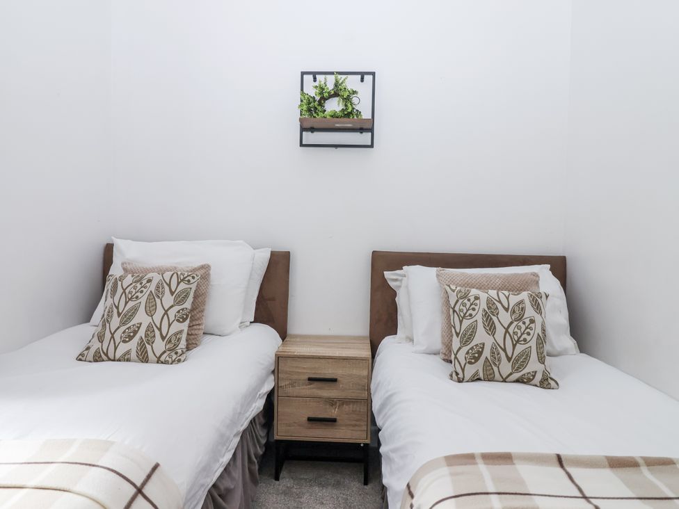 A bedroom with two beds and a side table at Valley Lodge 20 in Callington