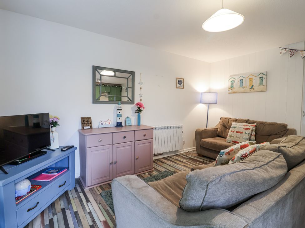 A living room with a television, sofa, and various decorative items at Manorcombe 21 near Honicombe Holiday Village