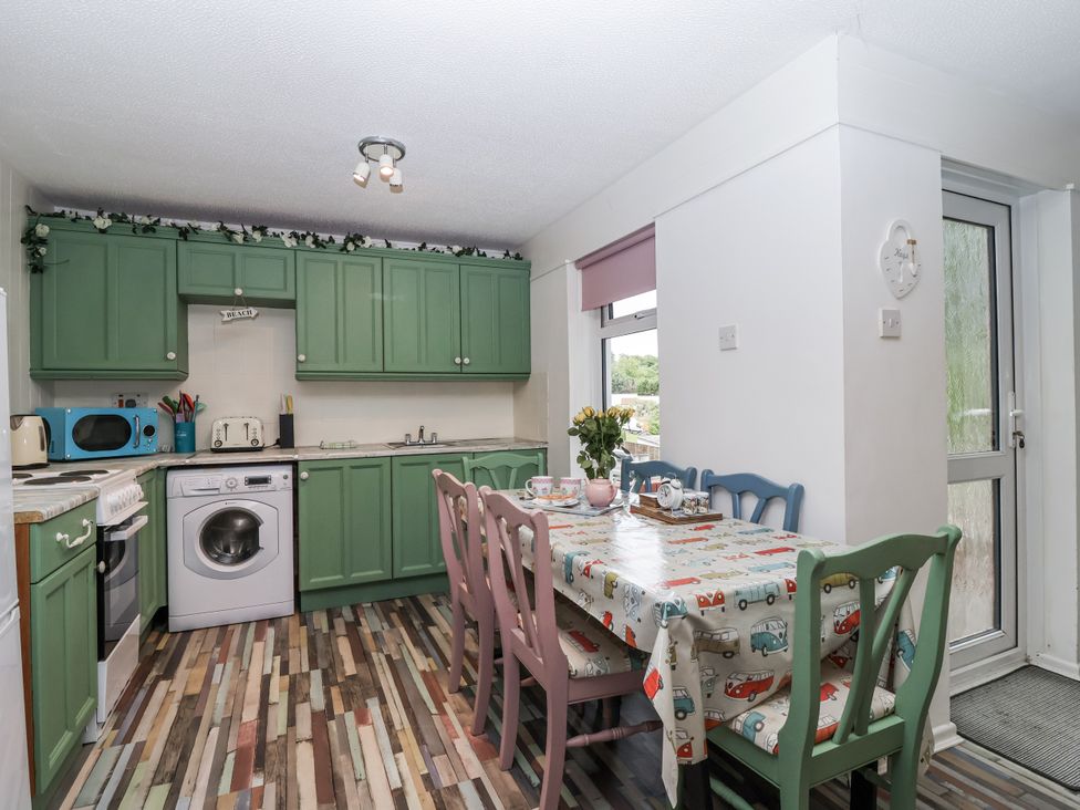 A kitchen with green cabinets and a dining table at Manorcombe 21 near Honicombe Holiday Village