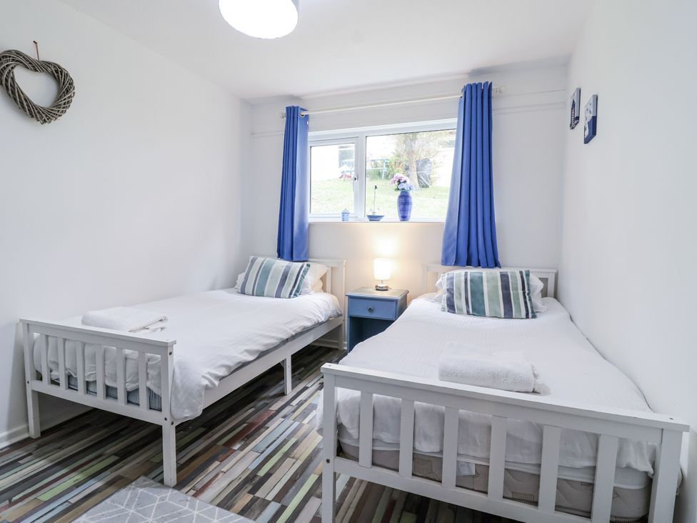 A bedroom with two single beds and a nightstand at Manorcombe 21 in Honicombe Holiday Village near Gunnislake