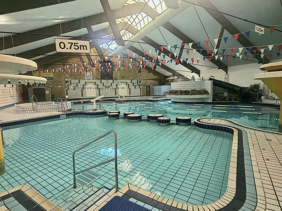 An indoor pool with a water slide and seating area at Manorcombe 21 in Honicombe Holiday Village near Gunnislake