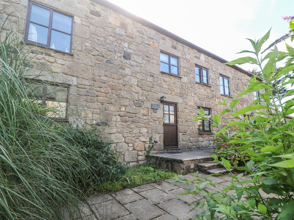 Exterior view of a stone building with windows and a door at Mill House Barn