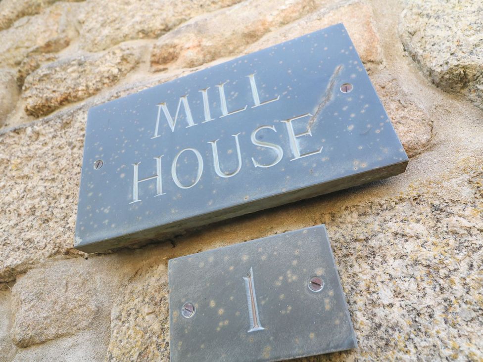 A sign with the name Mill House on a stone wall at Mill House Barn