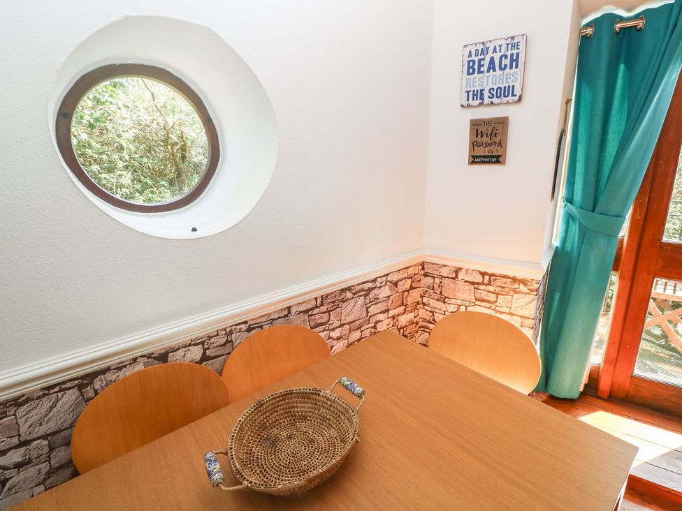 A dining room with a round window and a wooden table at Mill House Barn