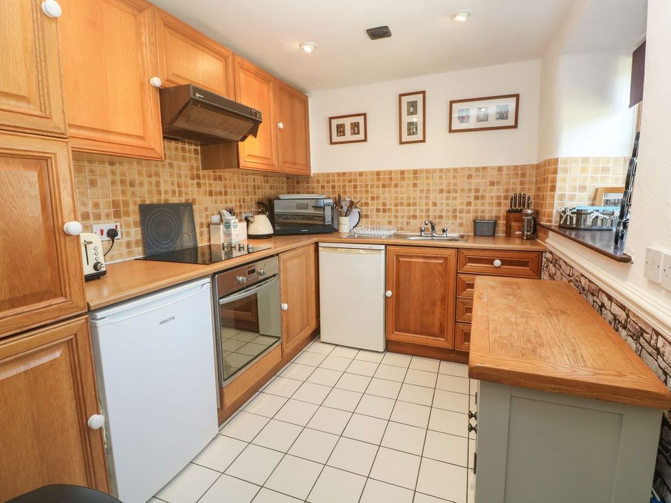 A kitchen with various appliances and wooden cabinets at Mill House Barn in 