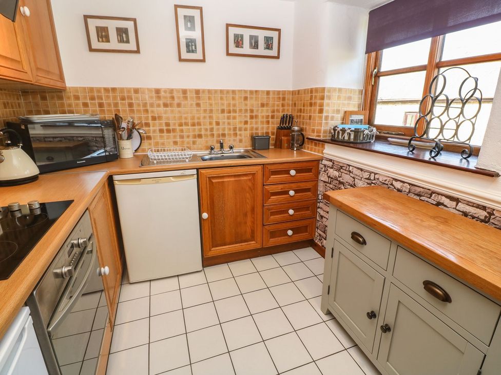 A kitchen with wooden cabinets and appliances at Mill House Barn