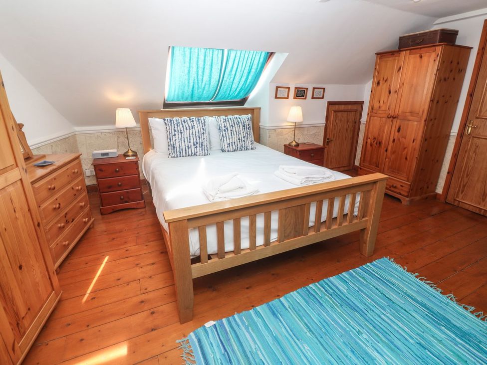 A bedroom with a bed and wooden furniture at Mill House Barn 