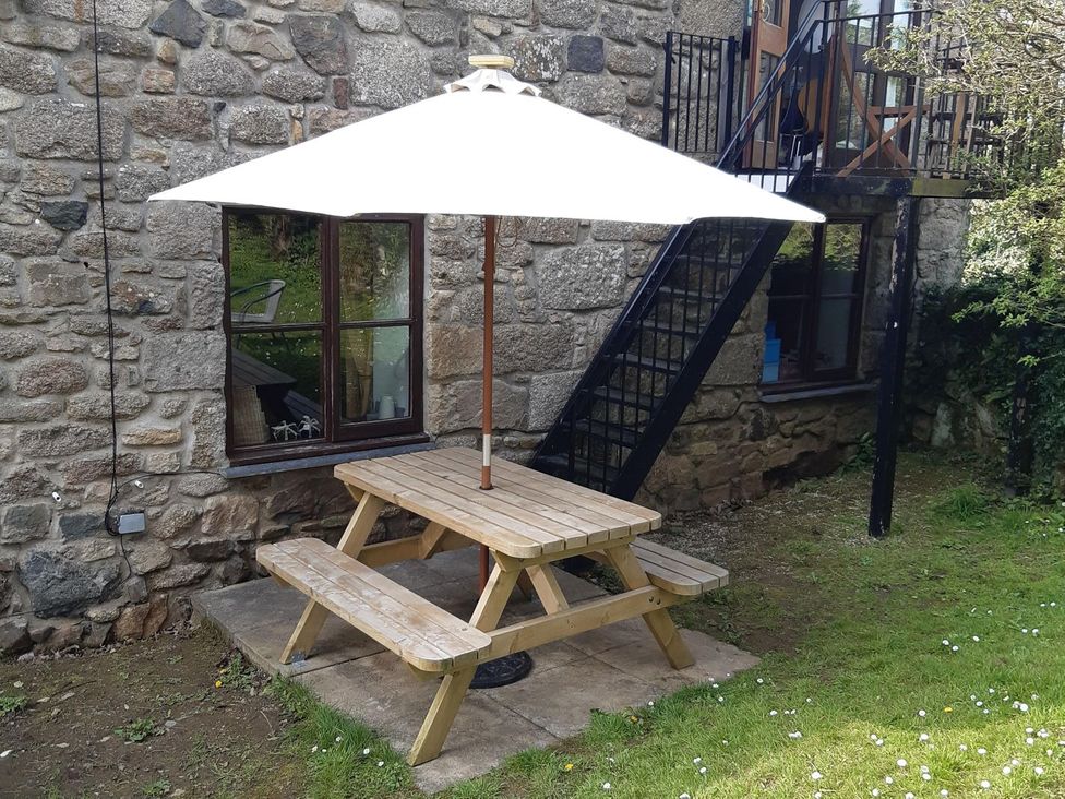 An outdoor seating area with a table and umbrella at Mill House Barn