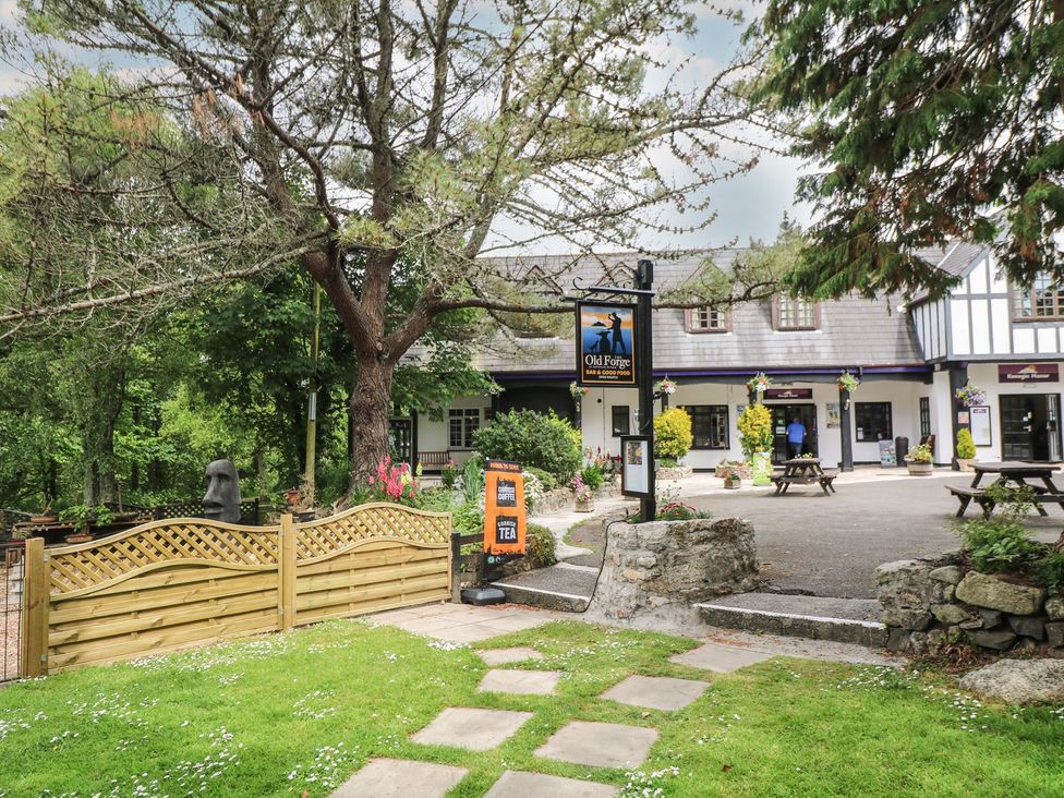 An outdoor area with a building, sign and seating at The Old Forge in 