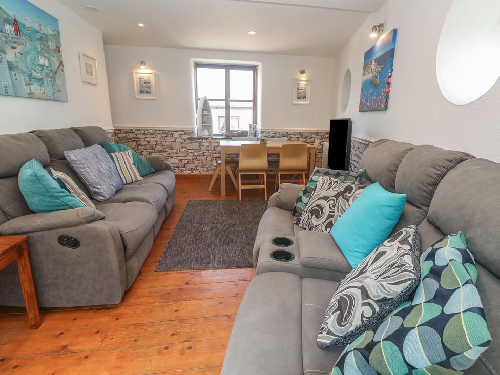 A living room with reclining sofas and a dining area at Mill House Barn in Gulval near Penzance