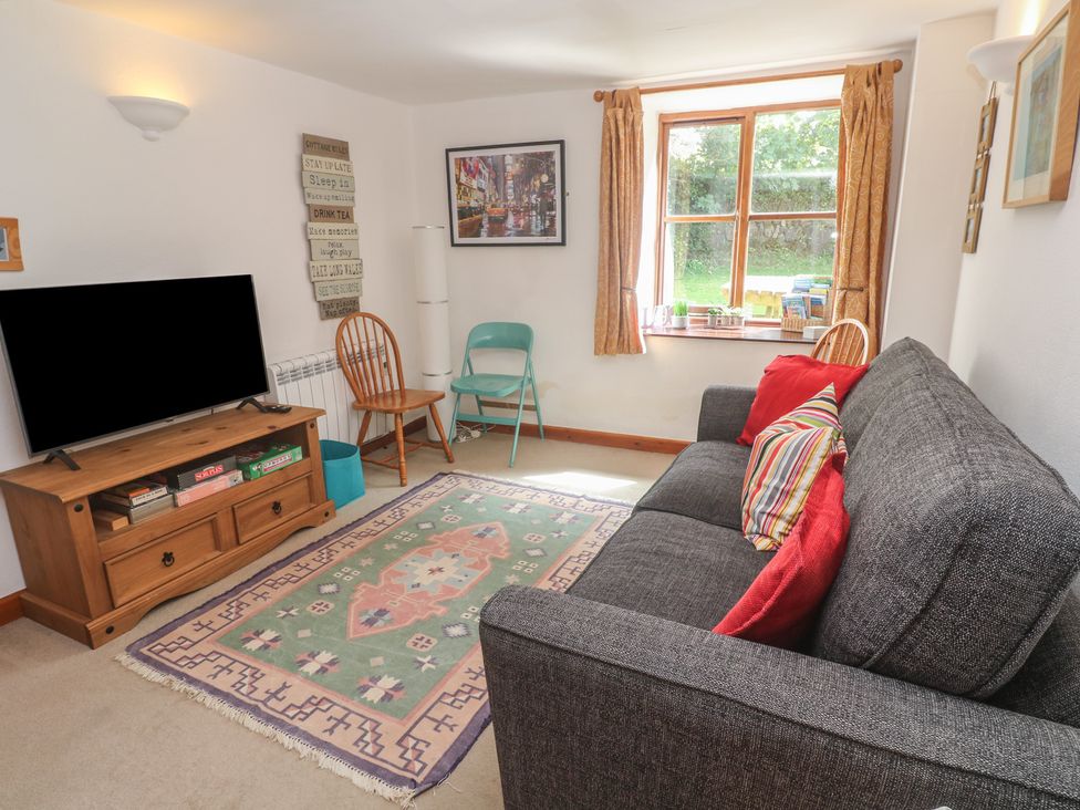 A living room with a sofa and a television at Mill House Barn in Gulval near Penzance