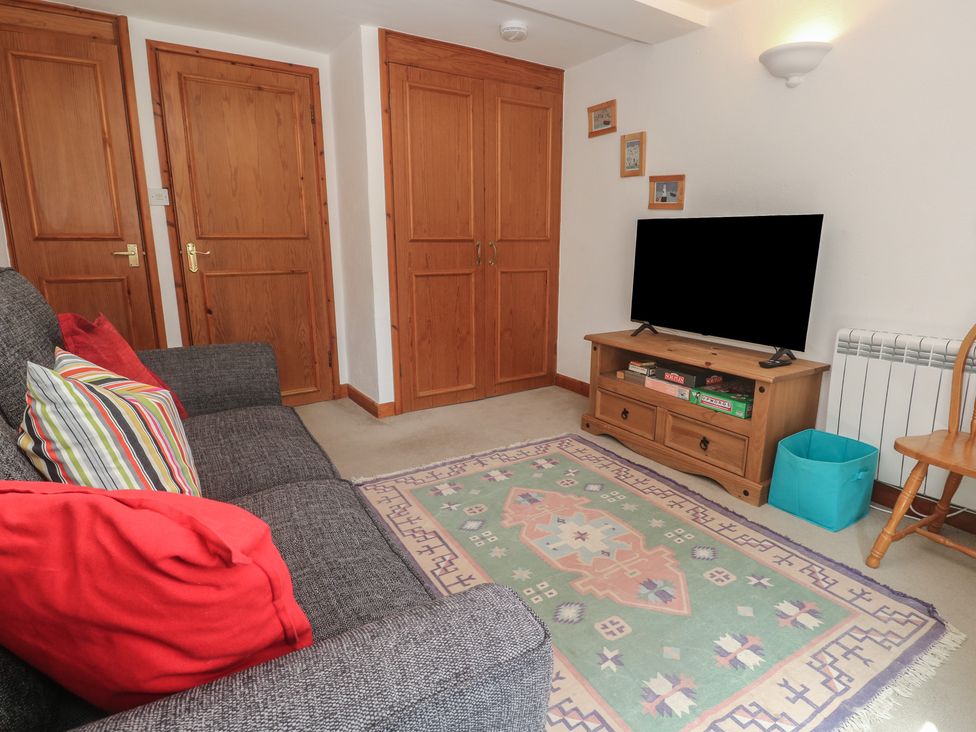 A living room with a sofa, television and rug at Mill House Barn in Gulval near Penzance