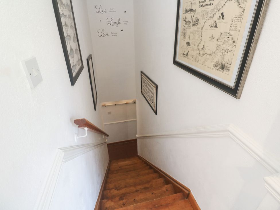 A staircase with wooden steps and framed pictures hanging on the wall at Mill House Barn Gulval near Penzance