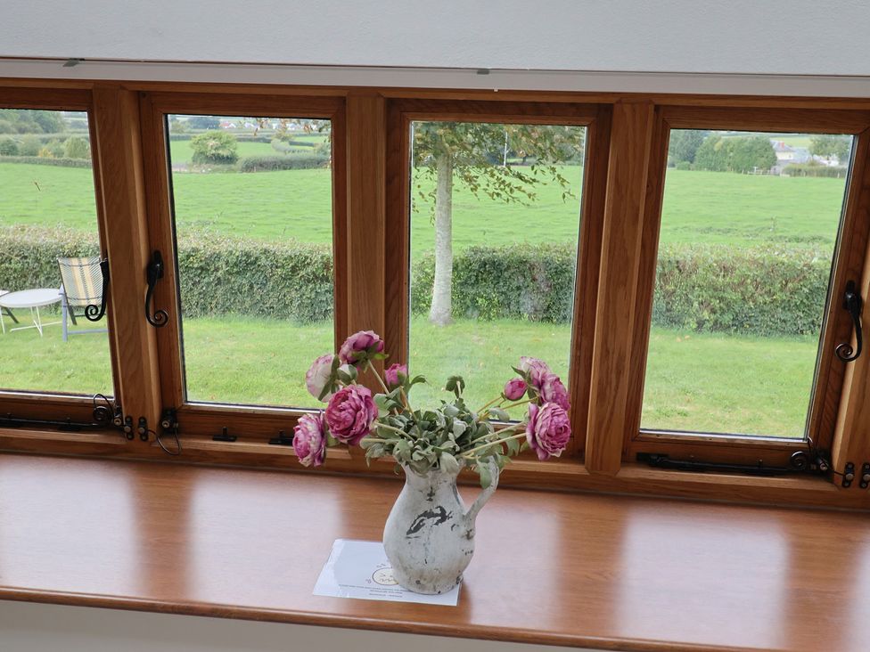 A window with a vase of flowers next to a table at The Dairy in 