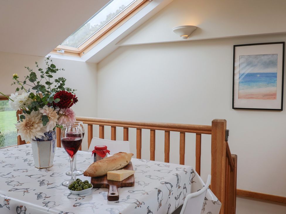 A dining room with a table set with bread, cheese, wine, and flowers at The Dairy in 